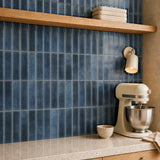 MORCART MT2212-XPE slate blue vertical linear wall tiles, oblique kitchen detail with an oak shelf and cream mixer, fine mottled print and a shallow glossy finish.