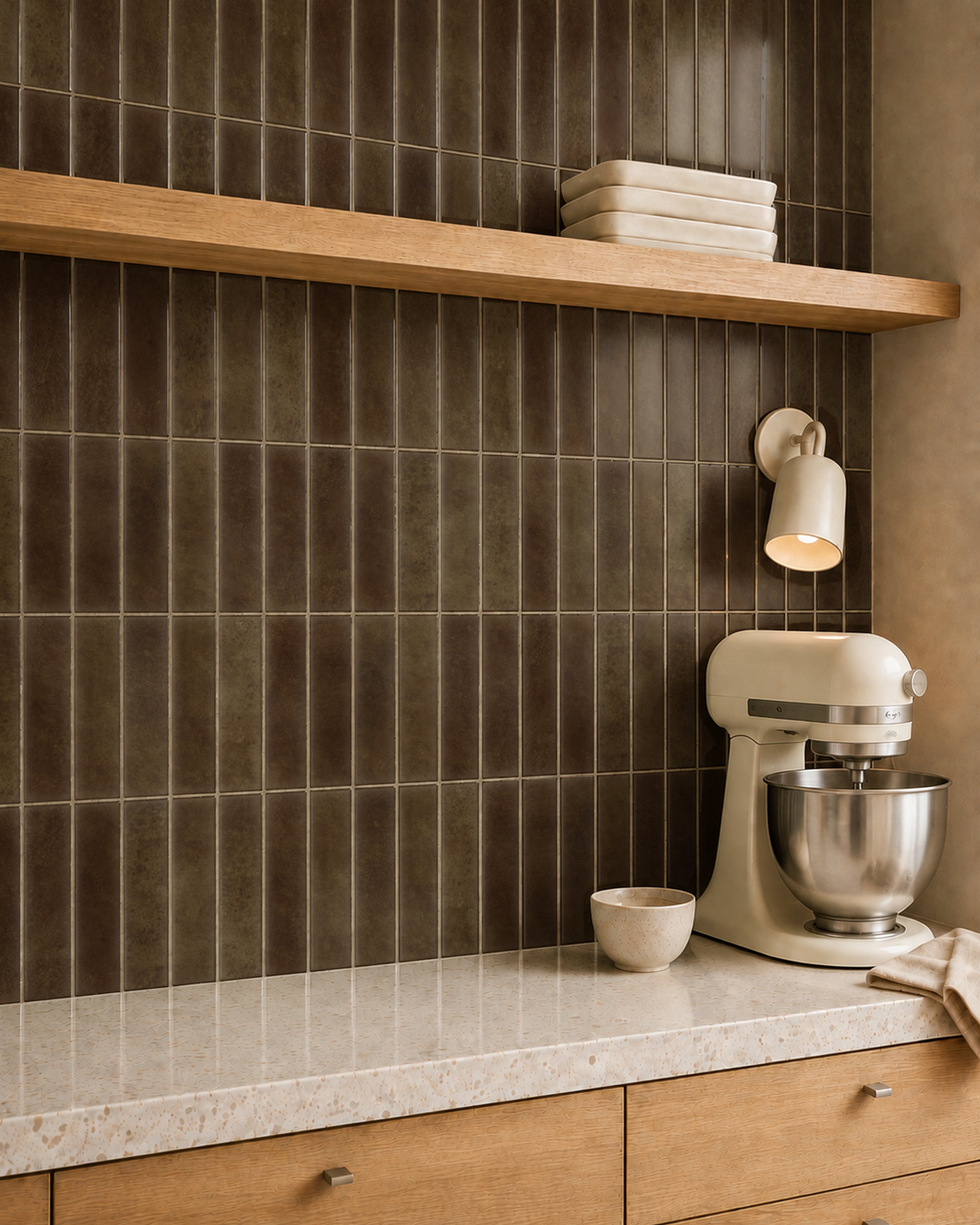 MORCART MT2415-XPE deep cocoa brown vertical linear wall tiles, oblique kitchen detail with an oak shelf and cream mixer, fine mottled print and a shallow glossy finish.